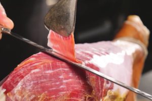 Experto cortando una loncha fina de jamón