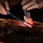 Manos de un profesional cortando una fina loncha de jamón ibérico.